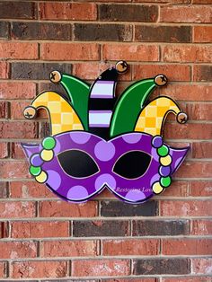 a mardi gras mask hanging on a brick wall