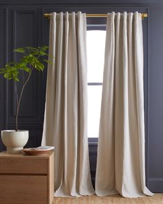 a white curtain hanging in front of a window with a potted plant next to it