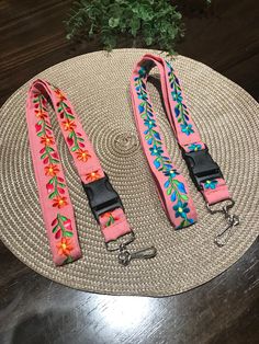 two pink leashes with flowers on them sitting on a round table next to a potted plant