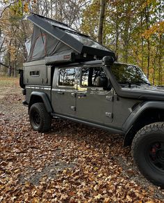 a black jeep parked in the woods with its tent on it's back end