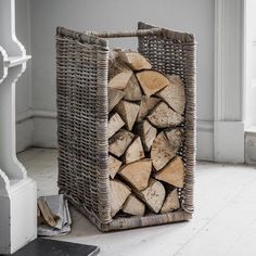 a stack of logs in a wicker basket on the floor next to a fireplace