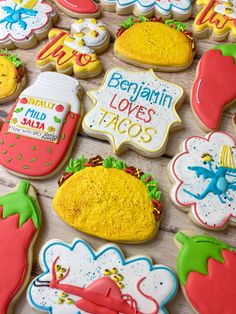 some decorated cookies are sitting on a wooden table and there is a sign that says, belgium loves tacos