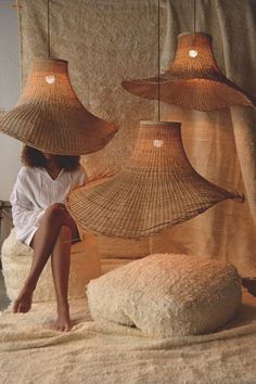 a woman sitting on top of a bed covered in lots of straw hat lamps hanging from the ceiling