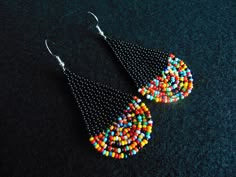 two pairs of beaded earrings on a black surface