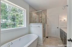 a bathroom with a tub, sink and large window in the corner that overlooks trees