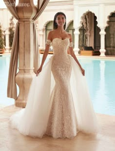 a woman standing in front of a pool wearing a wedding dress