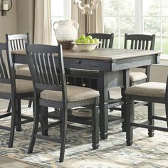 a dining room table with chairs and a bowl of fruit on top of the table