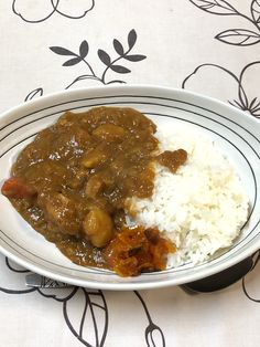 a white plate topped with rice and meat covered in gravy on top of a table