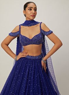 This stunning Blue Crystal and Sequin Embroidered Tulle Lehenga Set is a perfect blend of elegance and glamour. Crafted from soft net and georgette fabrics, the blue lehenga is intricately hand-embroidered and adorned with shimmering sequins that catch the light beautifully with every movement. Teamed with a jewelled blouse embellished with crystal detailing, it adds a touch of sparkle and sophistication, while the cold-shoulder design brings a modern twist to traditional wear. Completed with a matching dupatta, this lehenga set exudes grace. The off shoulder tassels can be added at an additional cost of GBP 45. Ideal for Sangeet, cocktail parties, or evening events. Composition : Lehenga, Dupatta - Soft Net and Blouse - Georgette Care: Dry Clean Only and Vacuum Storage This product can be Shoulder Tassels, Tulle Lehenga, Lehenga Dupatta, Blue Lehenga, Vacuum Storage, Indian Wedding Wear, Embroidered Tulle, Cocktail Parties, Net Dupatta