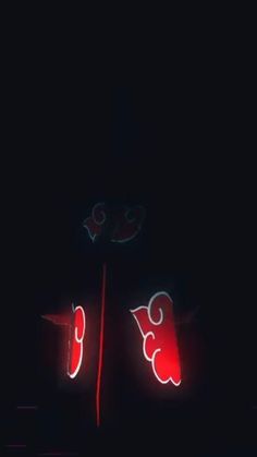 two red lights that are on the side of a building in the dark with no one around them