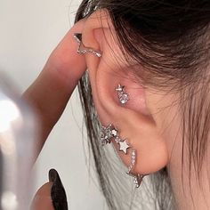 a woman is getting her ear pierced with star and moon piercings on their ears