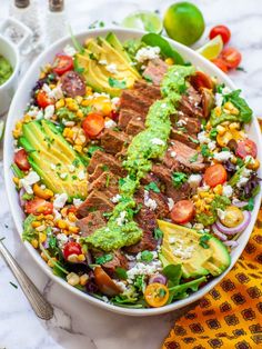 a large bowl filled with meat, vegetables and guacamole on top of a table