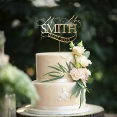 a three tiered wedding cake with white flowers and greenery sits on top of a tree stump