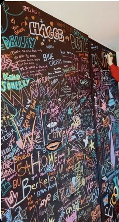 a man standing next to a blackboard covered in lots of writing on it's side