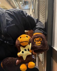 a person holding two stuffed animals in their hands and one is wearing a black jacket