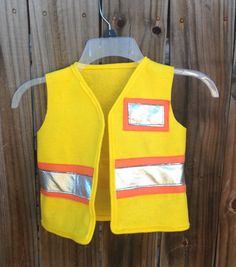 a yellow vest hanging on a wooden fence