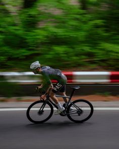 a bicyclist is riding down the road with trees in the back ground