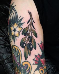 an arm with tattoos on it that has flowers and leaves in the middle of it