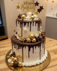 a three tiered cake with chocolate and gold decorations on the top is sitting on a wooden table