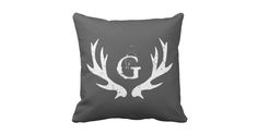 a grey pillow with white letters and antlers on the front, which reads g