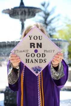 a woman in purple graduation gown holding up a sign