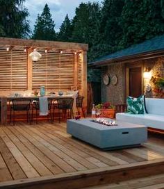 an outdoor living area with wooden decking and white couches on the outside patio