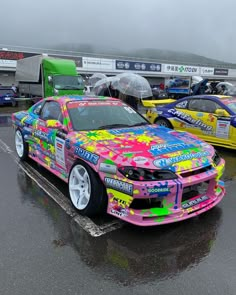 two colorful cars parked in a parking lot on a rainy day