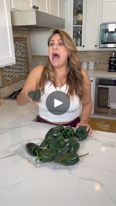 a woman standing in front of a counter with green peppers on it and an open mouth