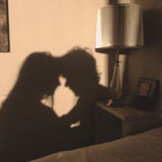 the shadow of a person's head on a bed next to a night stand