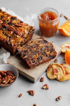 sliced fruit and nuts are on a cutting board next to oranges, pecans, and jam