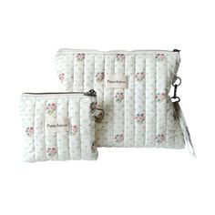 two bags with flowers on them sitting next to each other, one has a zippered pouch