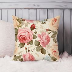 a pillow with pink roses on it sitting on a white furnishing next to a wooden headboard