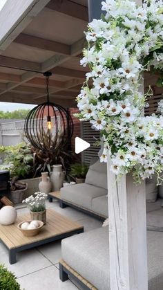 an outdoor living area with couches, tables and flowers