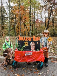 two children dressed up in costumes standing next to a sign