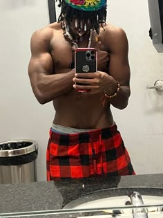 a man with dreadlocks taking a selfie in front of a bathroom mirror