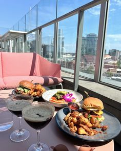 a table topped with plates of food and glasses of wine next to each other on top of a roof