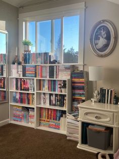 a living room filled with lots of books on top of a book shelf next to a window