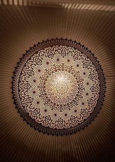 an intricate ceiling light in a room with shadows on the wall and below it is a circular pattern