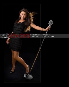 a woman in a black dress is holding a metal pole and posing for the camera