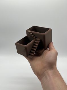 a hand is holding two chocolate cups in it