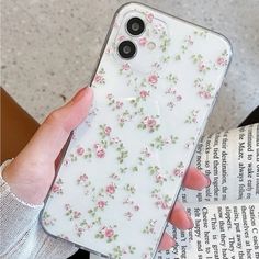 a woman holding up her phone case with flowers on it