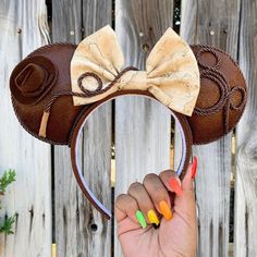 a hand holding up a mickey mouse ears headband