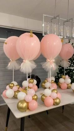 pink, white and gold balloons are arranged on a table