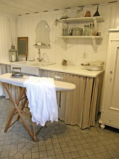 an old fashioned ironing board in the middle of a room with white walls and tile floors