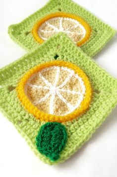 two crocheted coasters with orange slices on them, one is green and the other is yellow