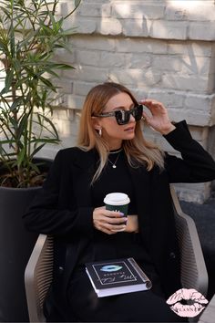 a woman sitting in a chair holding a cup of coffee