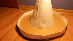 a white hat sitting on top of a wooden table next to a wall and floor