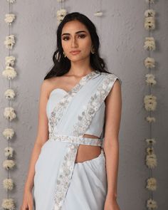 Description: The Classic Silhouette of a saree in ice blue, overlaid with whimsical details of a floral trellis border of hues of cream and silver. The saree is paired with a plain corset tube top blouse and embroidered belt.Colour Ice blueFabric GeorgetteCare Dry Clean onlyFit Tailored*Please note: The belt is included in the outfit Fitted Silver Pre-draped Saree For Designer Wear, Elegant Light Blue Choli For Festive Occasions, Elegant Light Blue Festive Choli, Fitted Silver Pre-draped Saree With Unstitched Blouse, Silver Pre-draped Saree For Wedding, Elegant Fitted Light Blue Lehenga, Fitted Silver Pre-draped Saree For Reception, Silver Pre-draped Saree With Sheer Dupatta, Light Blue Pre-draped Saree For Wedding