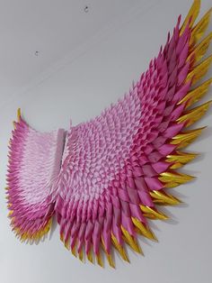 a large pink and yellow paper sculpture hanging on the wall