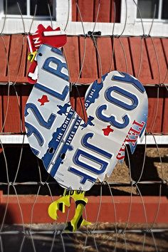 a couple of signs hanging from the side of a wire fence next to a building